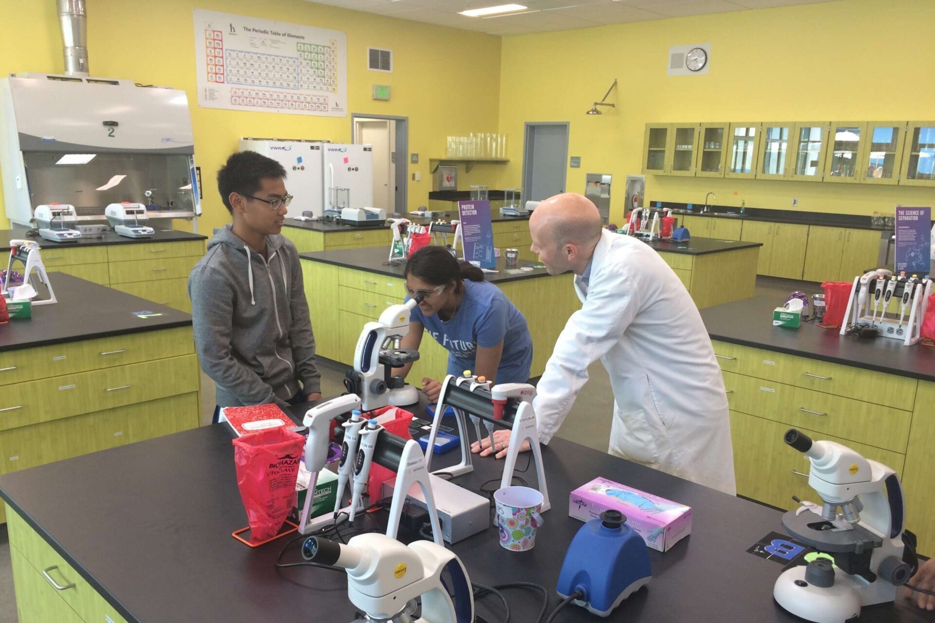 Students and a teacher using a microscope at the Science Garage at South San Francisco High School