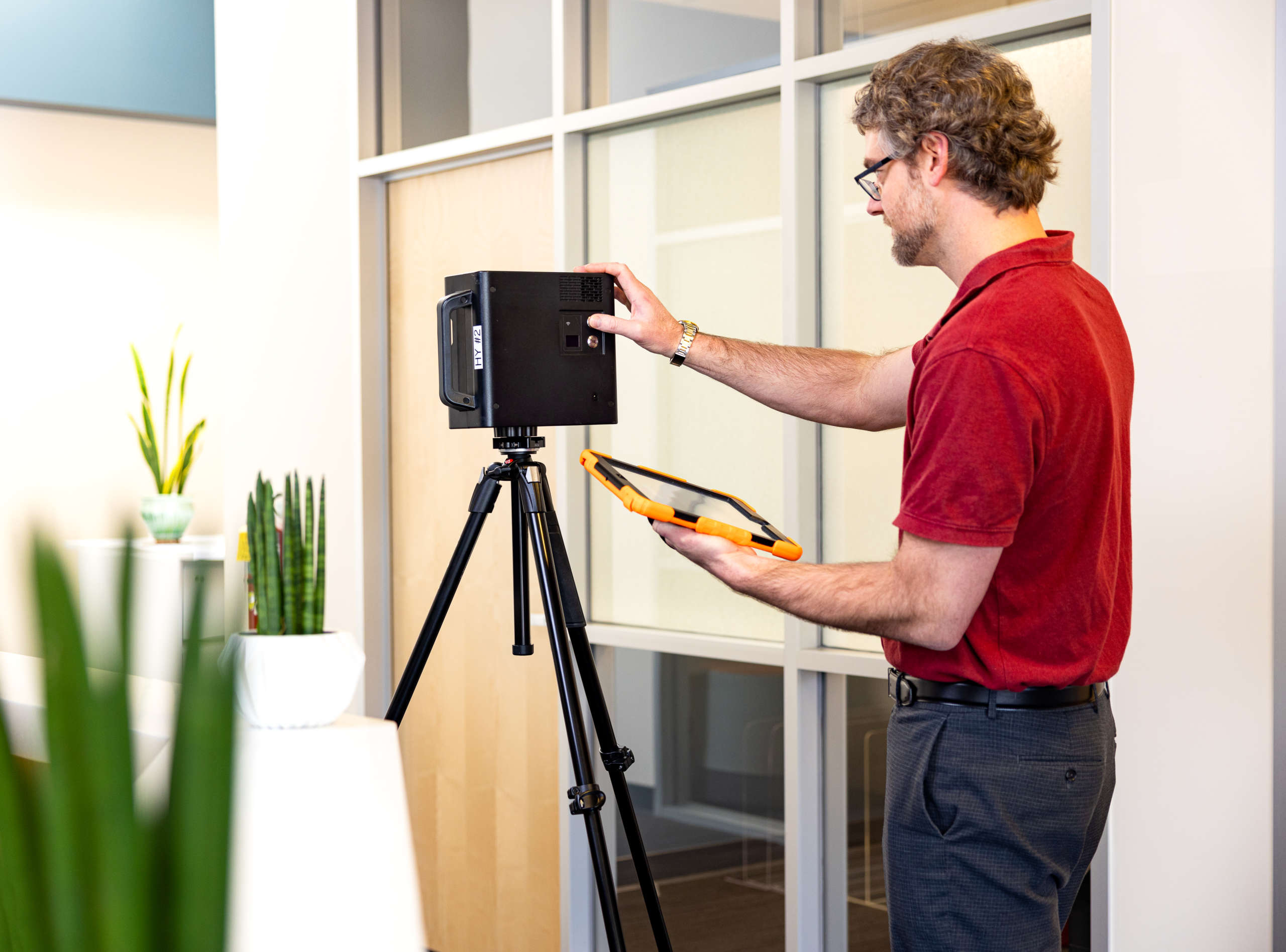 Man in office with tablet and device on tripod